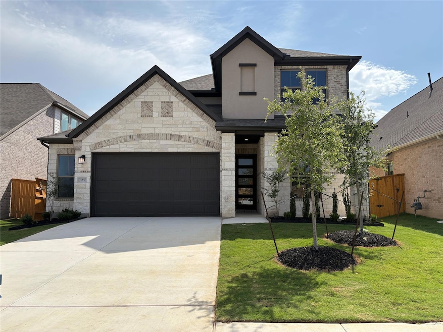 French country home featuring driveway, stone sid