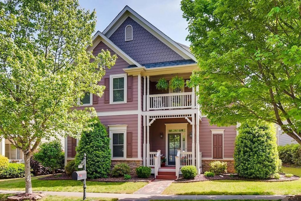 View of front of property featuring a balcony, a porch, a front yard, and stone siding