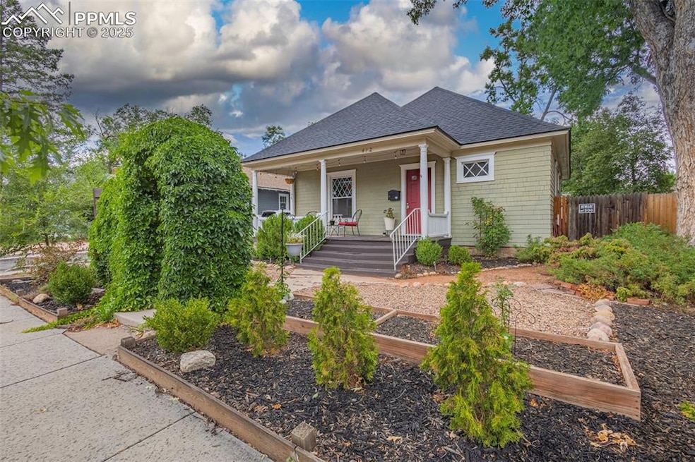 Bungalow featuring covered porch, roof with shingles, a vegetable garden, and fence