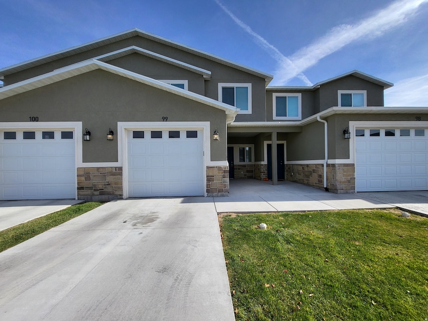 View of front of home with stucco siding, stone siding, a front yard, and concrete driveway