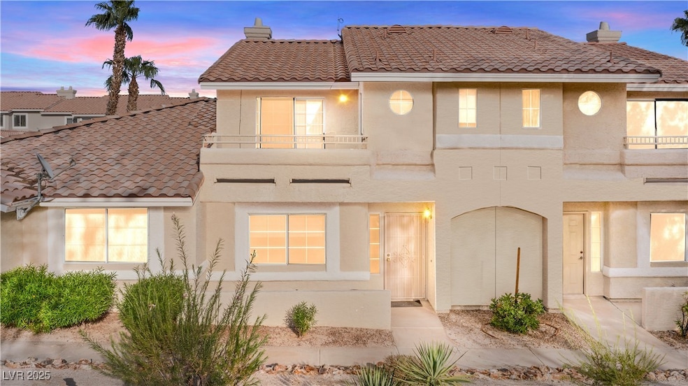 View of front of property with a chimney, a balcony, and stucco siding