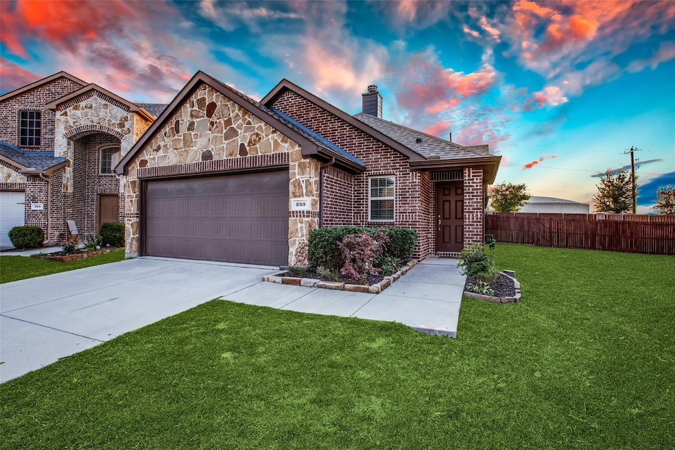 View of front of house with stone siding, a chimney, driveway, a garage, and brick siding