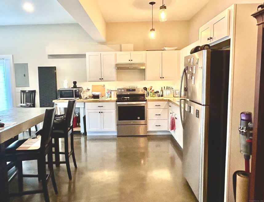 Open plan kitchen with stainless appliances, white