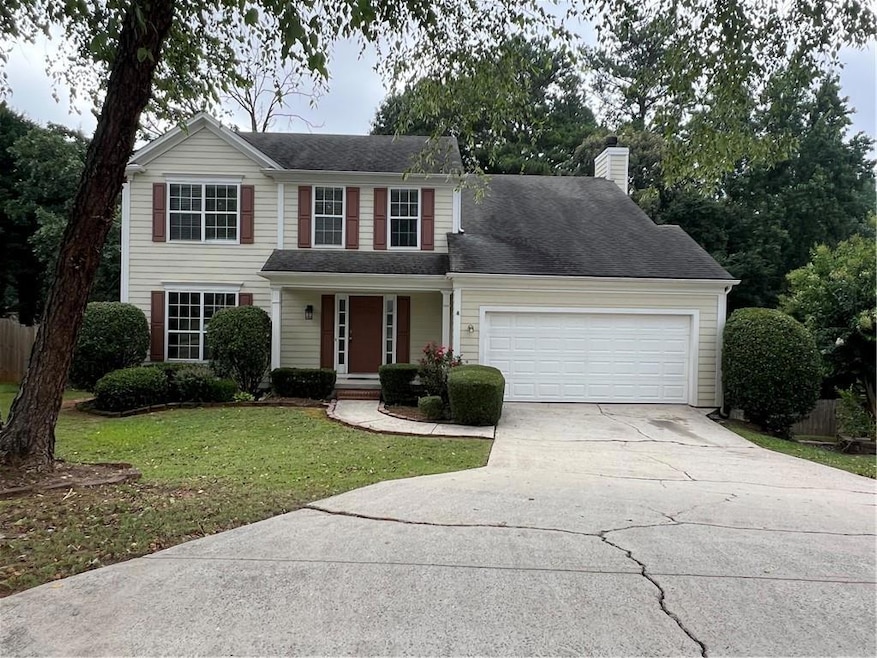 Traditional home with concrete driveway, an attached garage, and a chimney