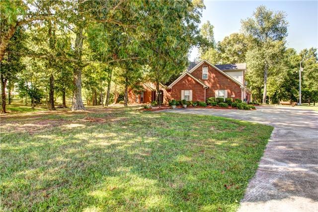 Front view of home with concrete driveway and turn around, beautifully landscaped with large trees in front yard!