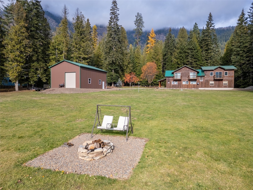 View of home featuring an outdoor fire pit, an outdoor structure, and a wooded view