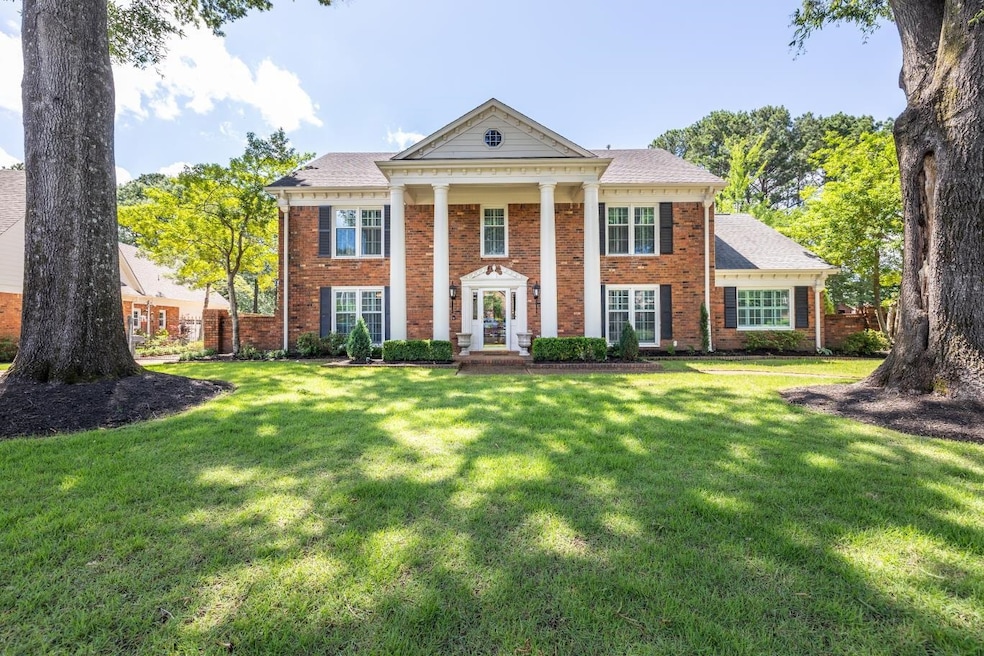Neoclassical / greek revival house featuring brick siding and a front yard