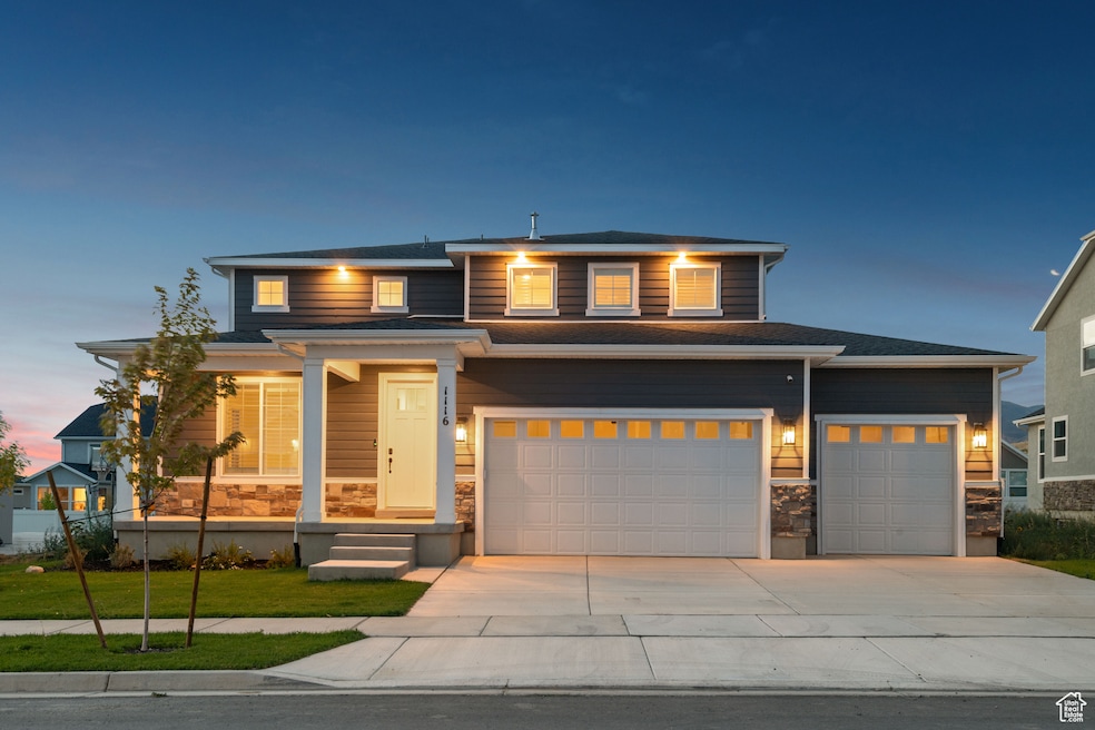 View of front facade with stone siding and driveway