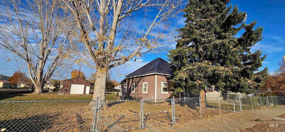 View of property exterior with a fenced front yard, a gate, and an outbuilding