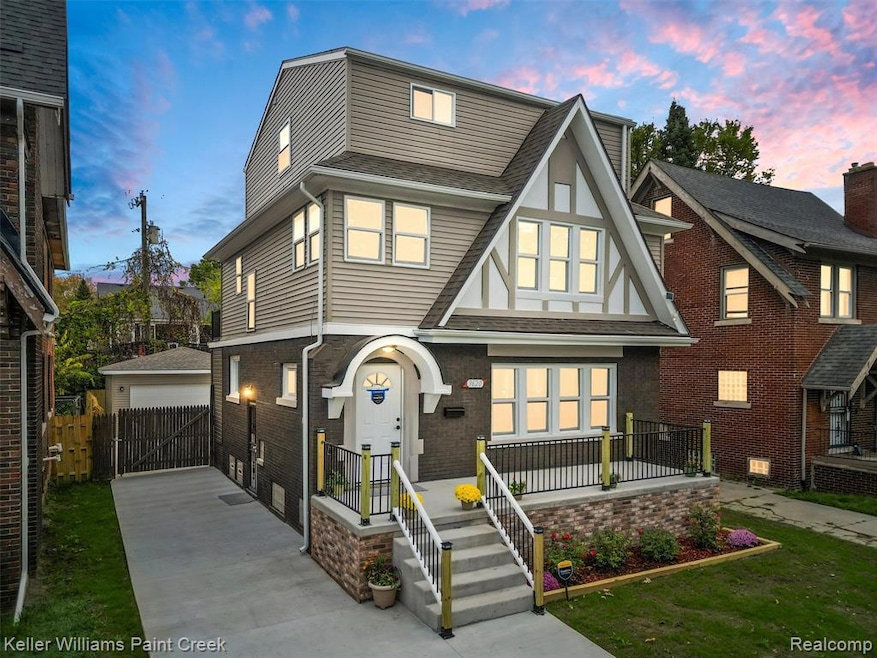 Tudor house featuring a shingled roof, brick siding, a garage, and concrete driveway