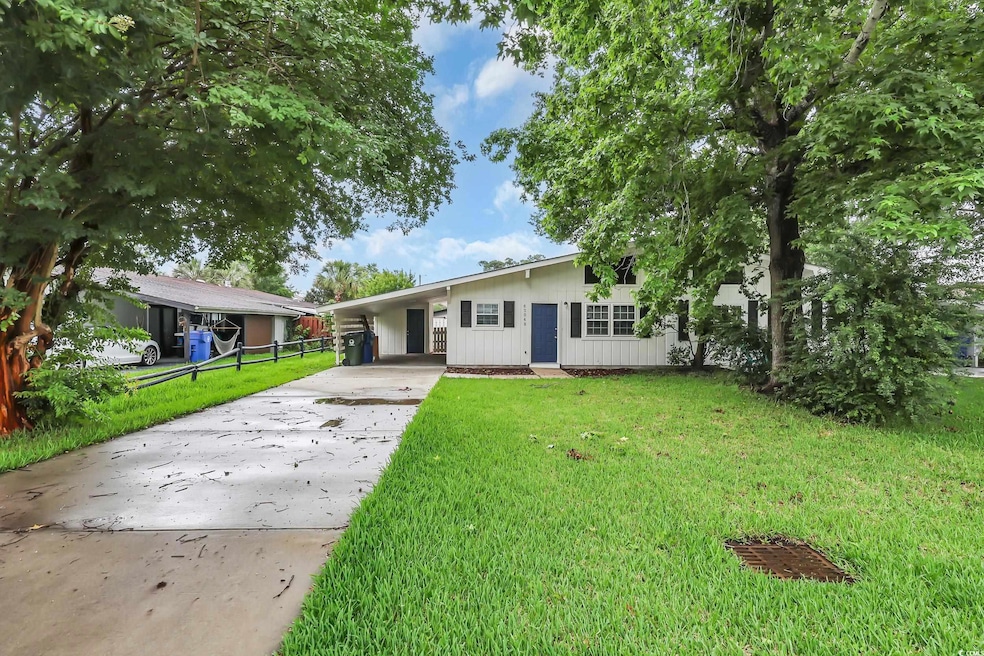 Single story home featuring concrete driveway and a carport