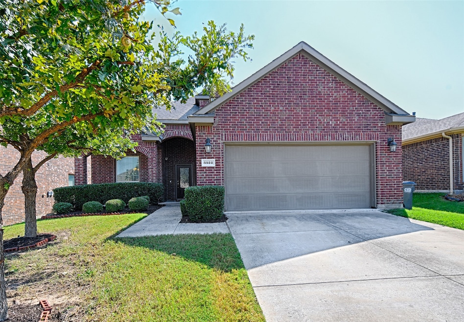 View of front of house with concrete driveway, brick siding, a front lawn, and a garage