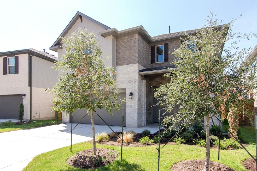 View of front of home with concrete driveway, bri
