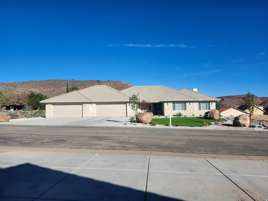 Ranch-style home featuring concrete driveway, a mountain view, a garage, a front yard, and a chimney
