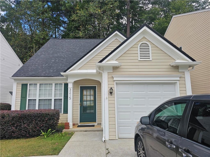 View of front facade featuring a shingled roof and a garage
