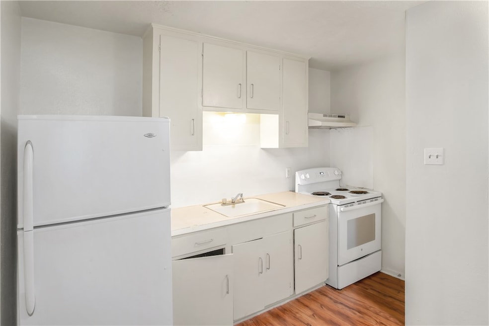 Kitchen featuring white appliances, a sink, under
