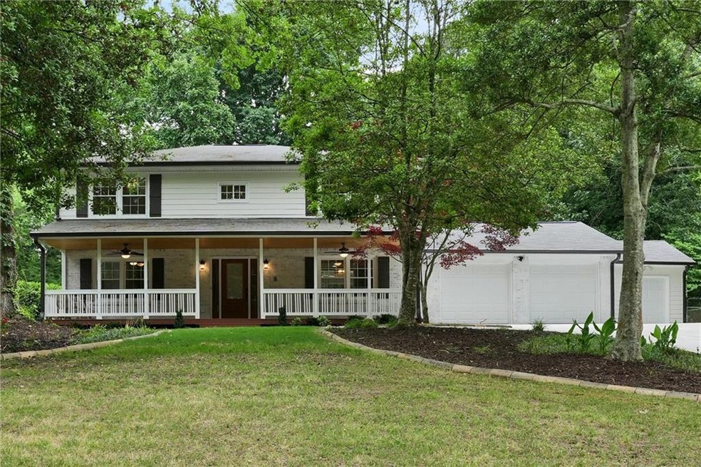 View of front facade featuring covered porch, two car garage, a tool room/mini-garage and front yard