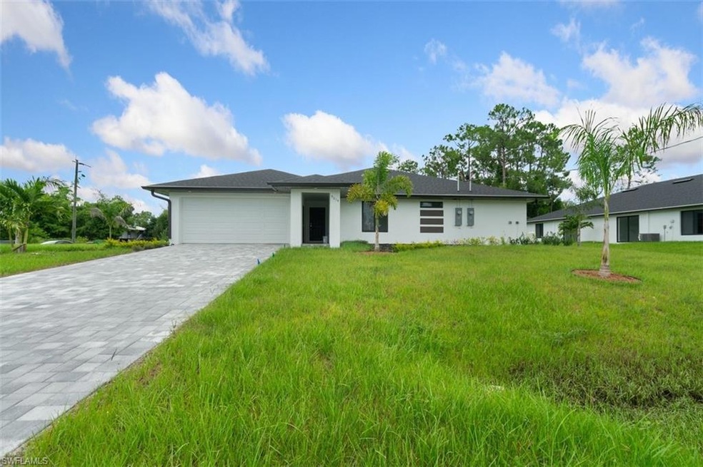 Ranch-style home with a front lawn, a garage, decorative driveway, and stucco siding