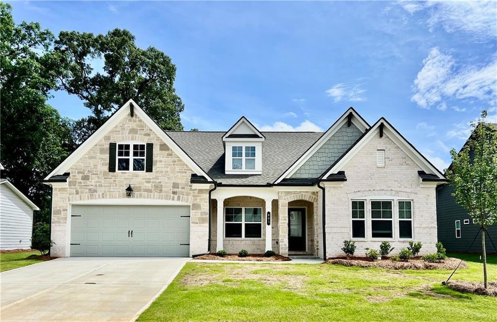 View of front of property featuring a front yard, concrete driveway, a garage, a shingled roof, and stone siding