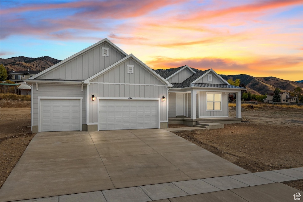 View of front of home featuring board and batten siding, a mountain view, a garage, and a porch