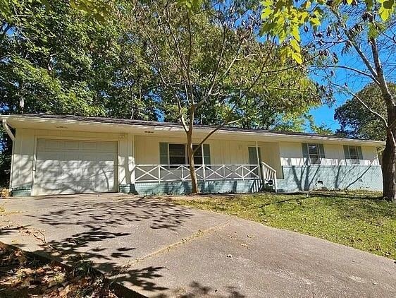 Single story home featuring a garage, board and batten siding, a front lawn, and driveway