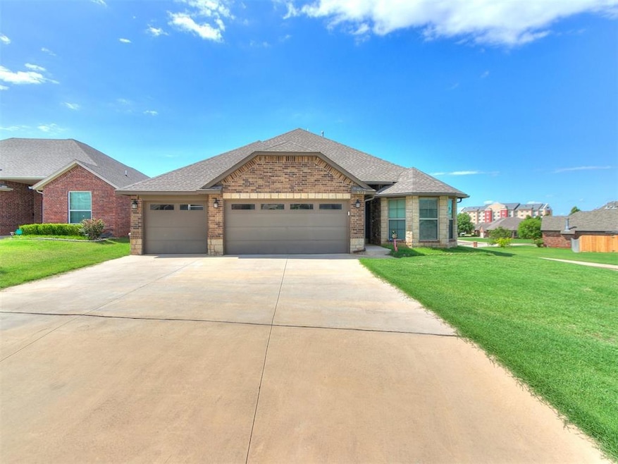 View of front of home with concrete driveway, a garage, a front yard, and brick siding