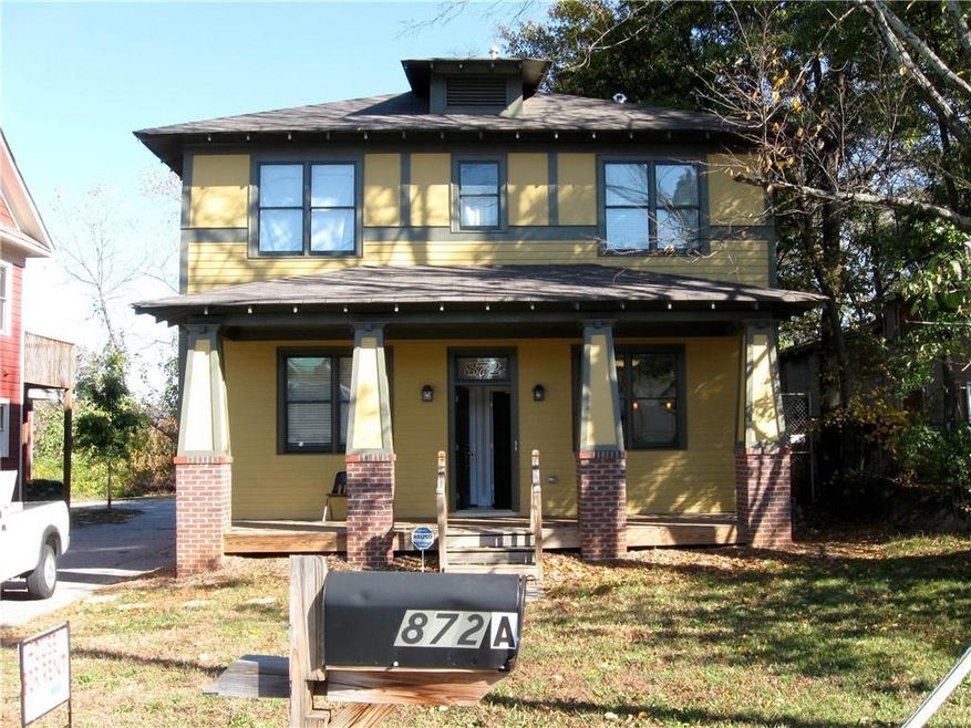 American foursquare style home with a porch, brick siding, and a shingled roof