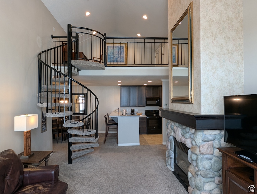 Carpeted living room with a high ceiling and a fireplace