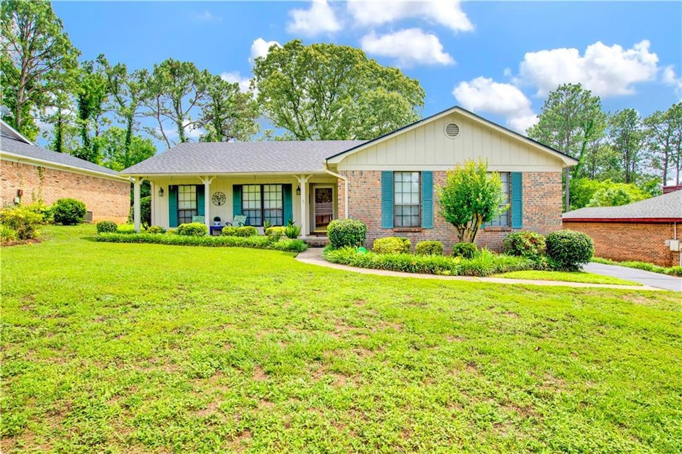 Single story home with brick siding, a porch, and a front lawn