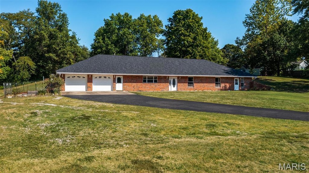 Ranch-style house with a front lawn, driveway, brick siding, and an attached garage