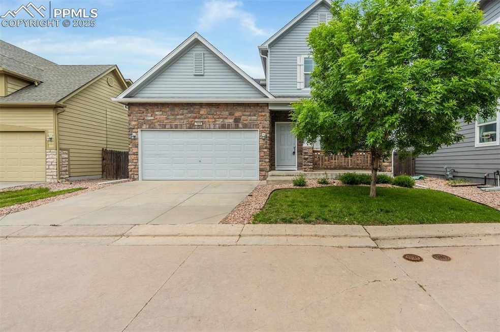 View of front facade featuring concrete driveway, a front yard, a garage, and stone siding