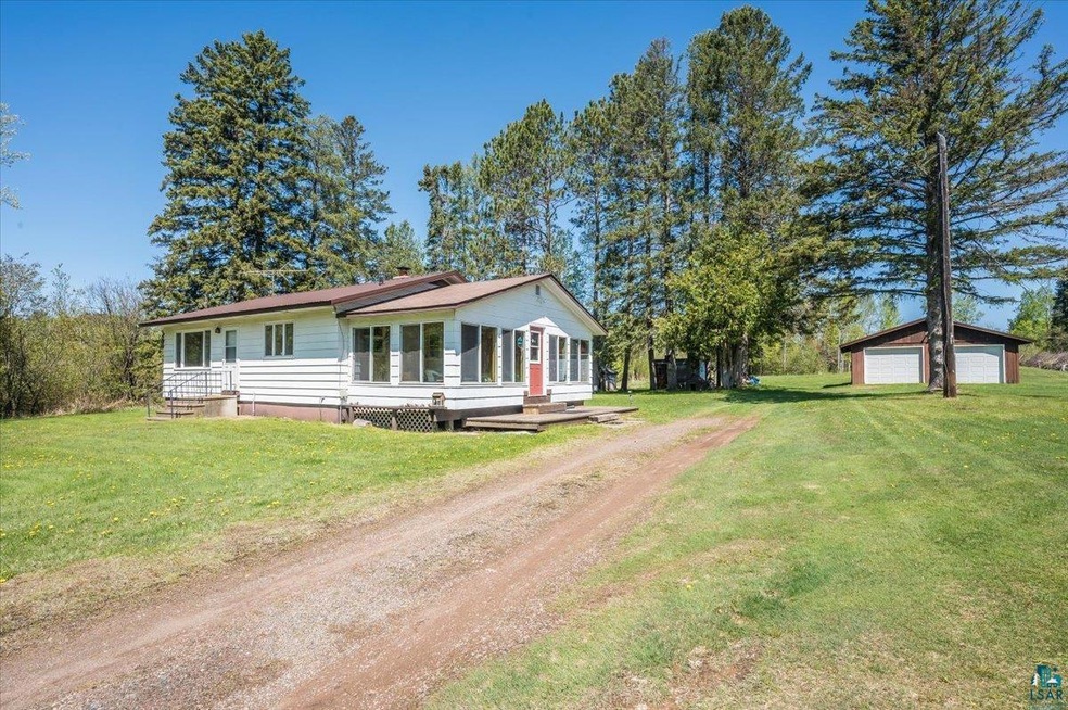View of front facade with driveway, a garage, a front lawn, and an outdoor structure