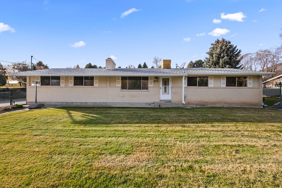 Ranch-style home featuring a chimney, brick siding, and a patio