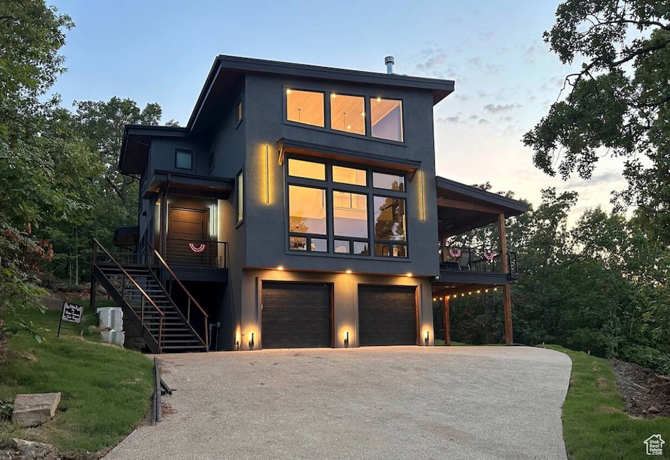 Contemporary house featuring stucco siding, driveway, stairs, and a garage