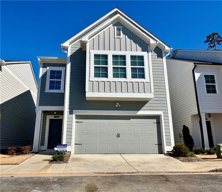 View of front of property with concrete driveway, central AC unit, board and batten siding, and an attached garage