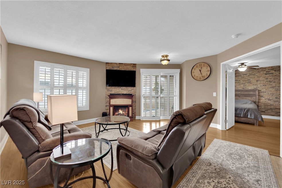 Living area with a stone fireplace, light wood-typ