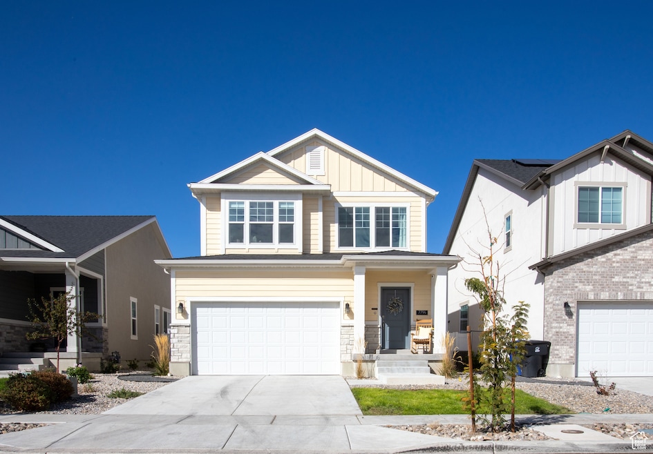 View of front of house with board and batten siding, a porch, driveway, and an attached garage