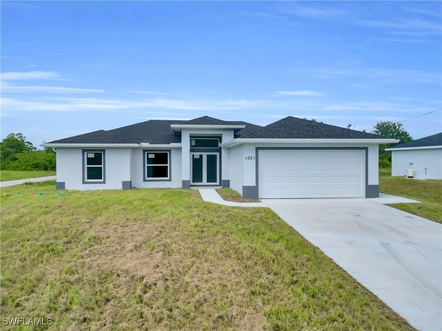 Prairie-style house with stucco siding, concrete driveway, a shingled roof, and a front yard