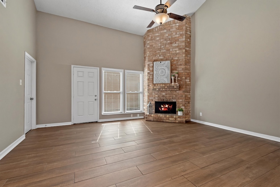 The spacious family room offers soaring vaulted ceilings and an abundance of natural light. The stunning floor-to-ceiling brick fireplace creates a cozy ambiance.