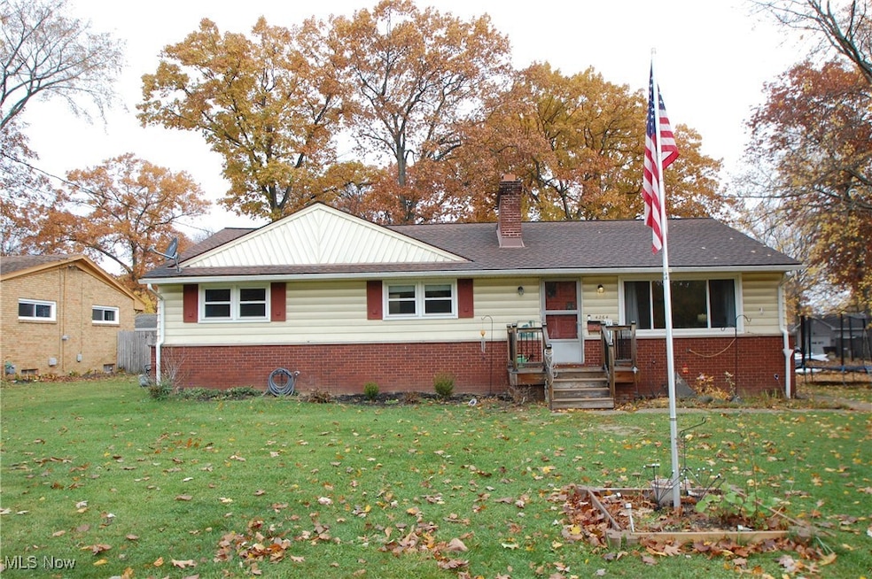 Ranch-style house featuring a front yard, a chimney, and brick siding