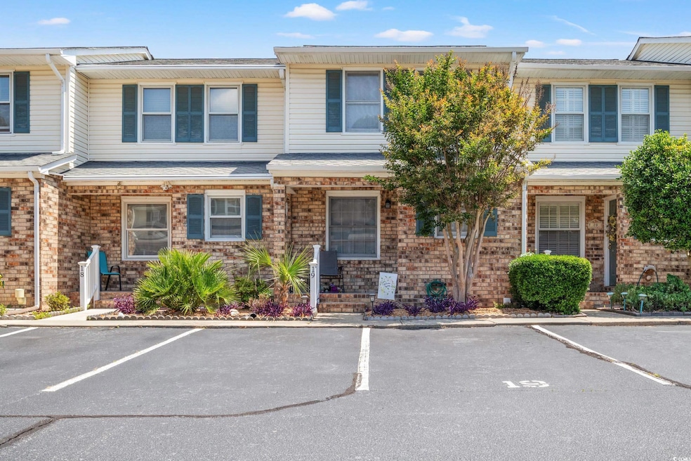 Townhome / multi-family property featuring uncovered parking and brick siding