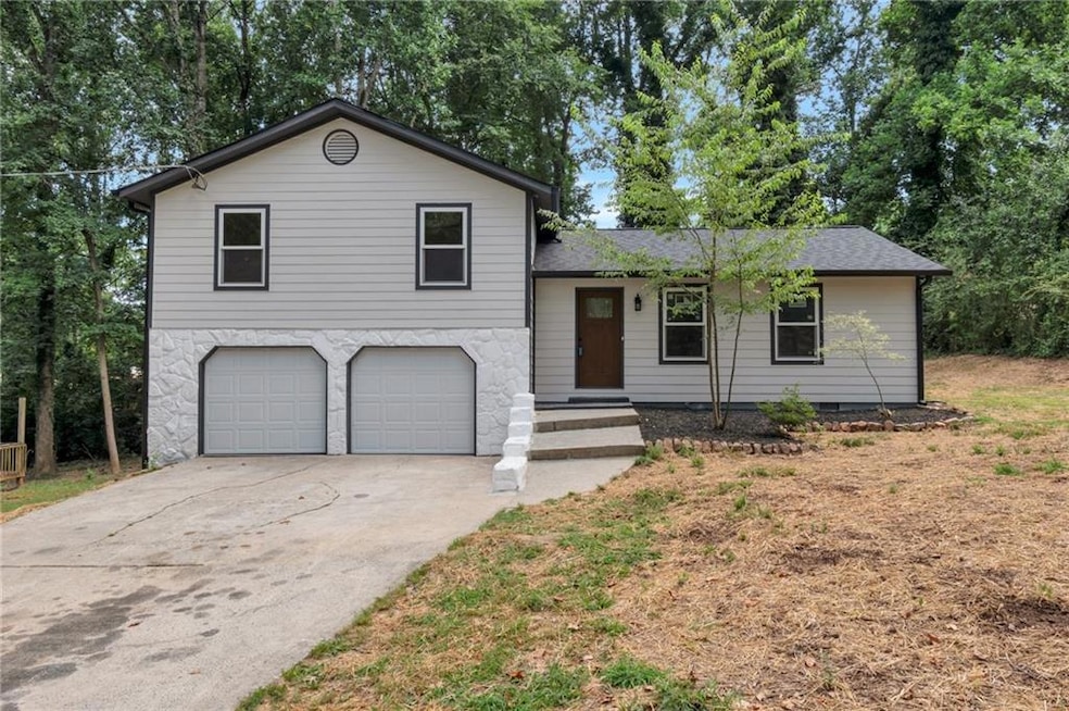 Split level home with an attached garage, concrete driveway, and roof with shingles