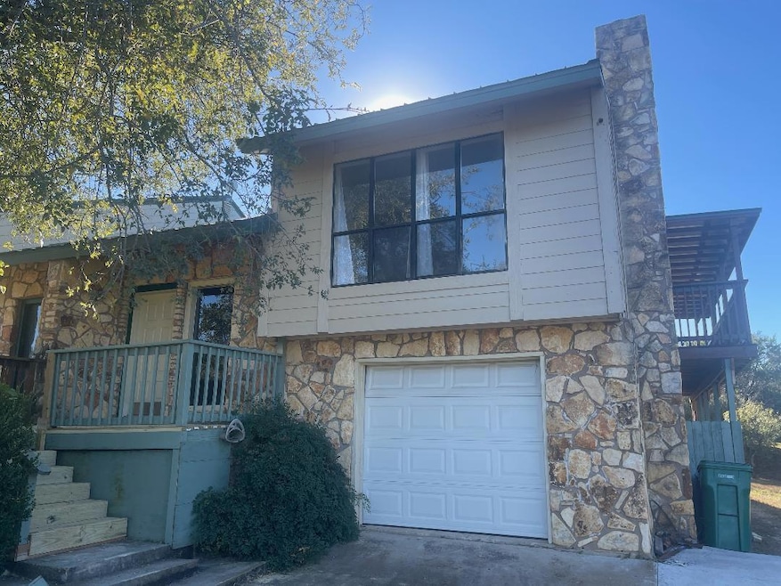 View of front of house featuring stone siding, a balcony, and an attached garage