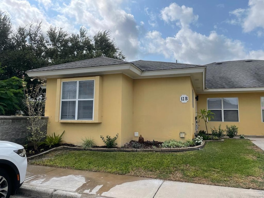 View of front of house with stucco siding, roof with shingles, and a front yard