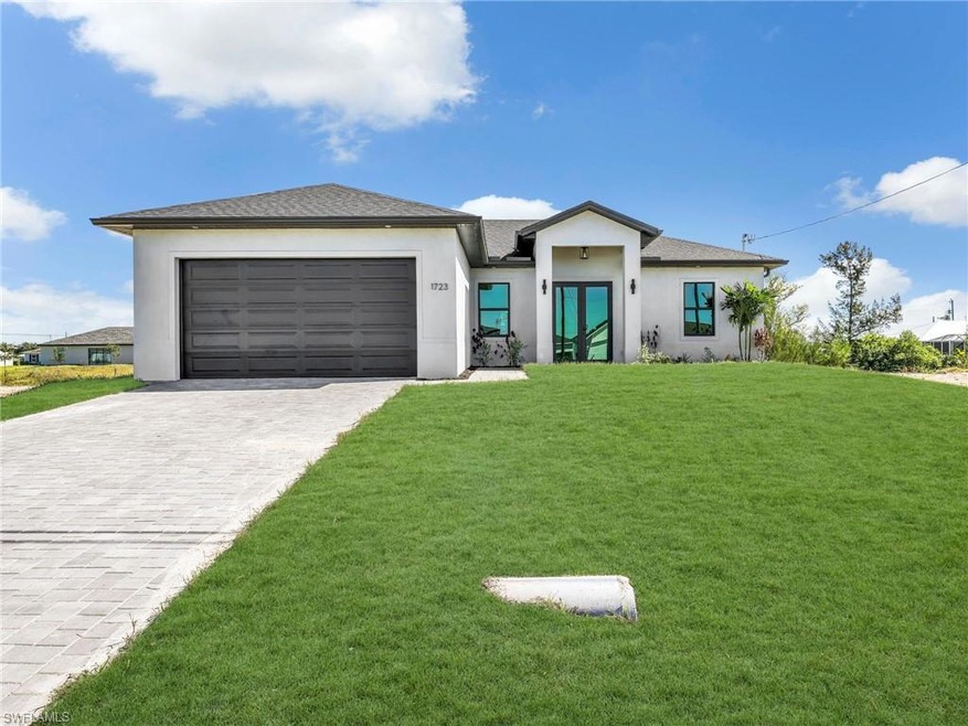 View of front of house featuring stucco siding, decorative driveway, a front yard, and an attached garage