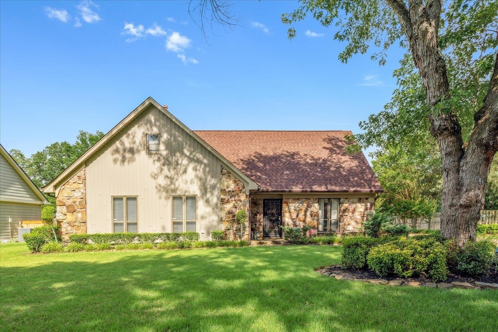 Tudor-style house featuring stone siding, a front yard, and roof with shingles