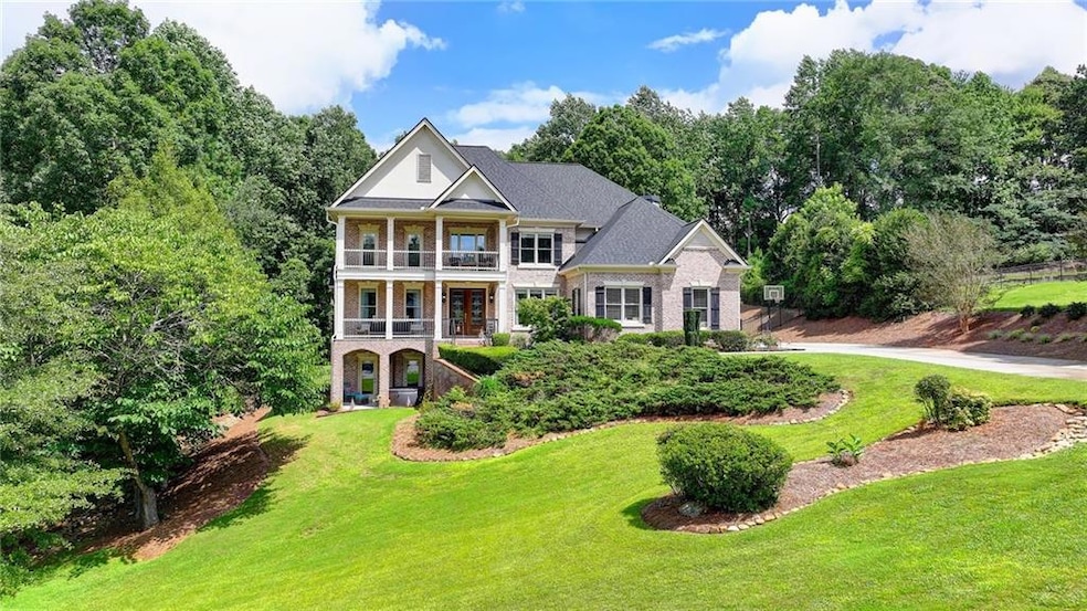 Neoclassical home featuring a balcony, a front lawn, brick siding, and covered porch