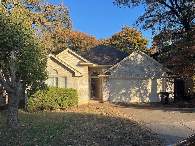 Single story home featuring a garage, brick siding