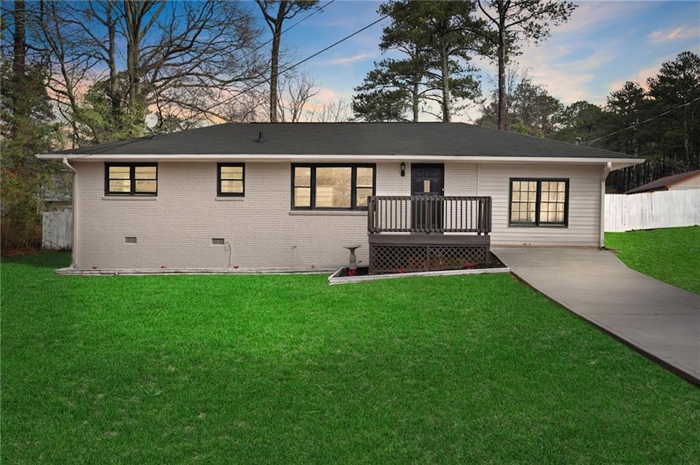 Ranch-style home featuring a wooden deck and a law