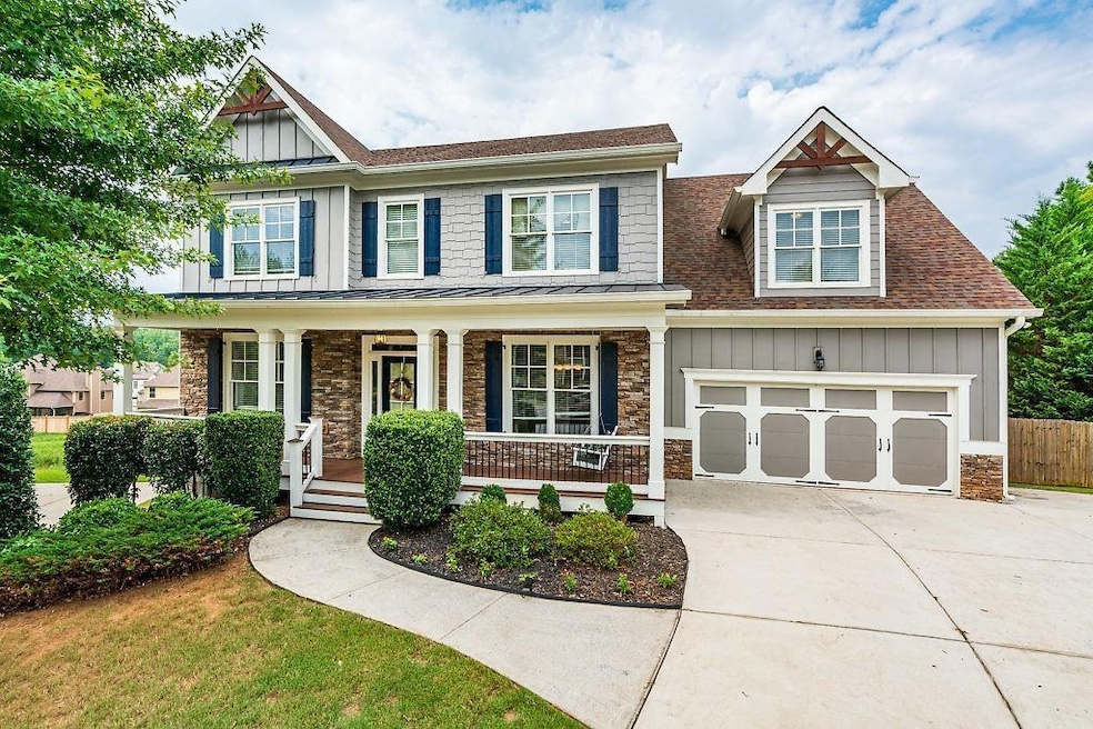 Craftsman house featuring board and batten siding, concrete driveway, covered porch, stone siding, and a shingled roof